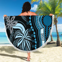 Round beach blanket with blue tribal pattern, white fringe border, held open outdoors