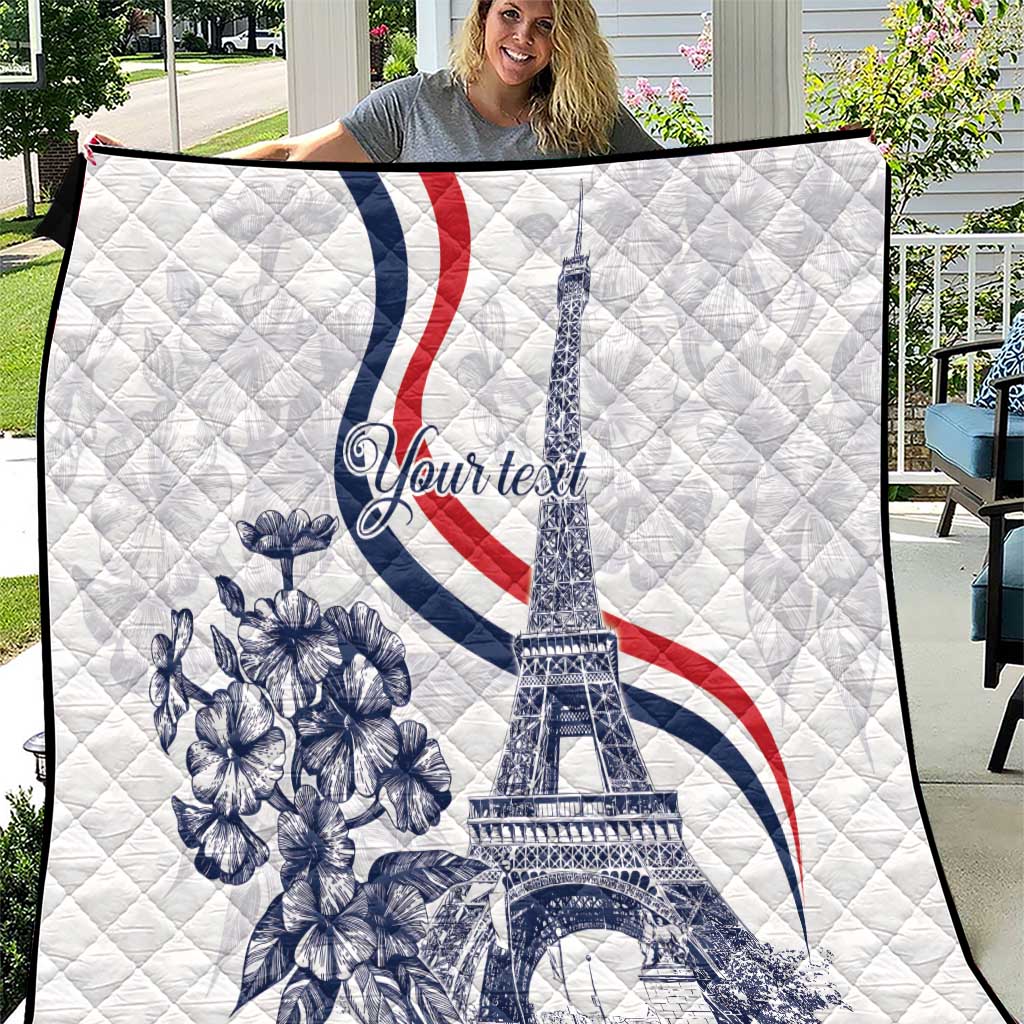 White quilt with Eiffel Tower, blue flowers, and red and navy curved stripes.