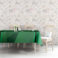 Green tablecloth with sporty pattern over dining table with chairs and decor.