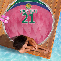 Pink round beach blanket with fringe, crest logo, and green “YOUR TEXT” number 21