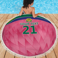 Pink round beach blanket with fringe, crest logo, and green “YOUR TEXT” number 21