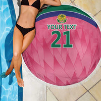 Pink round beach blanket with fringe, crest logo, and “YOUR TEXT” number 21 on poolside
