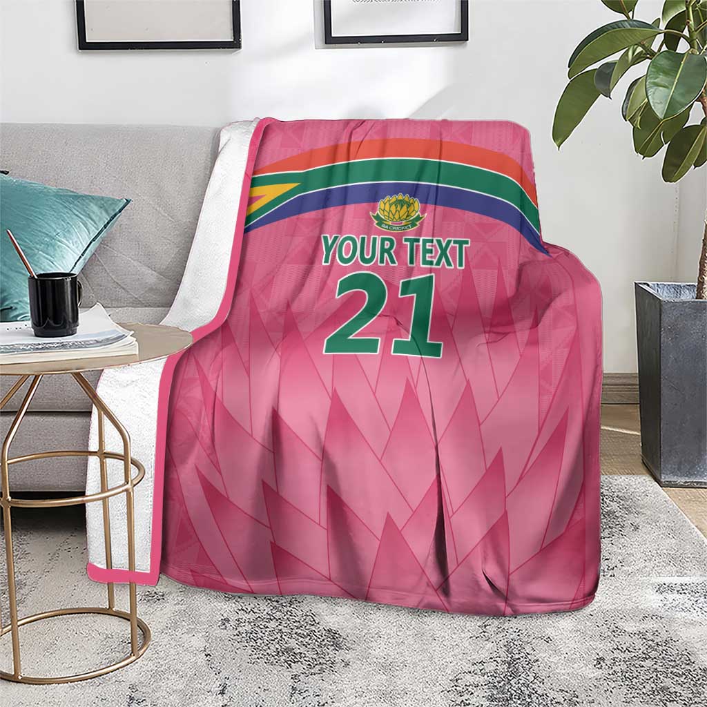 Pink custom cricket blanket with Proteas crest and YOUR TEXT 21, draped on sofa