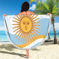 Round light blue beach blanket with fringe, sun face graphic and text, draped outdoors.