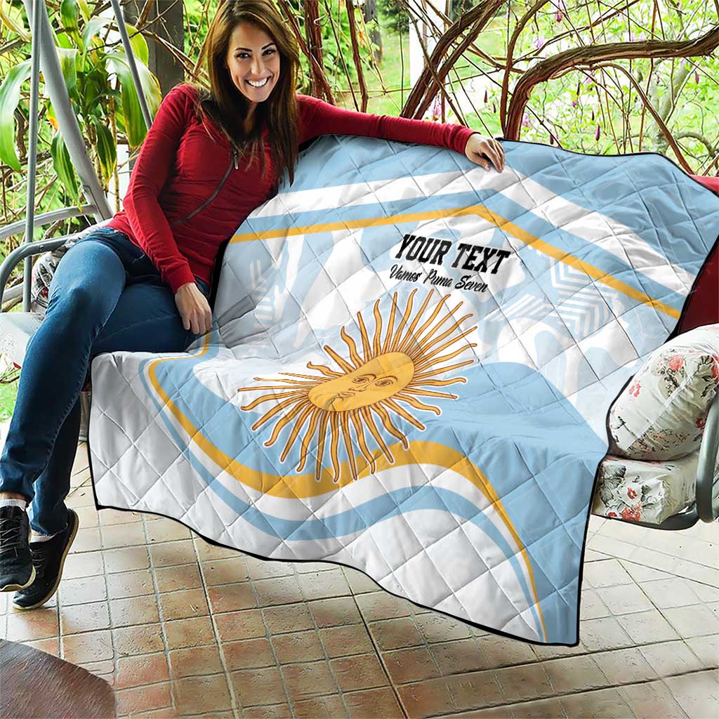 Light blue and white quilt draped on a sofa with Argentina sun face and custom text