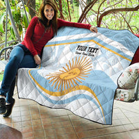 Light blue and white quilt draped on a sofa with Argentina sun face and custom text
