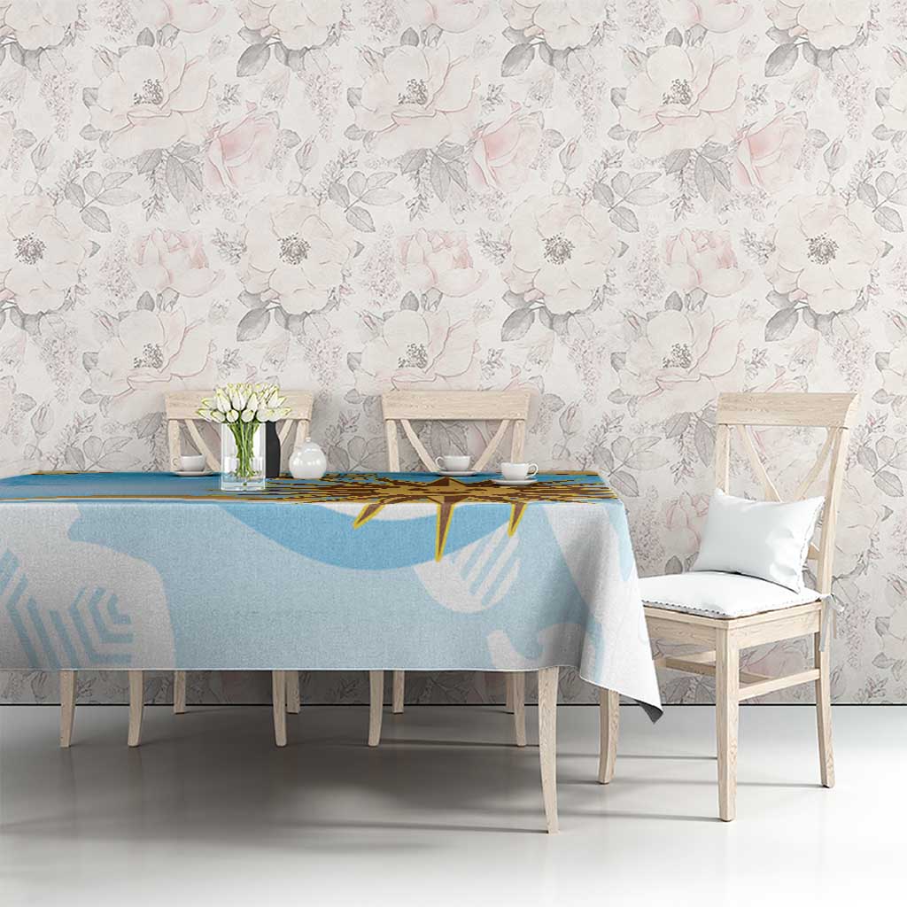 Blue tablecloth with gold sun graphic and abstract shapes, with vase and cups on table