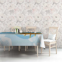 Blue tablecloth with gold sun graphic and abstract shapes, with vase and cups on table