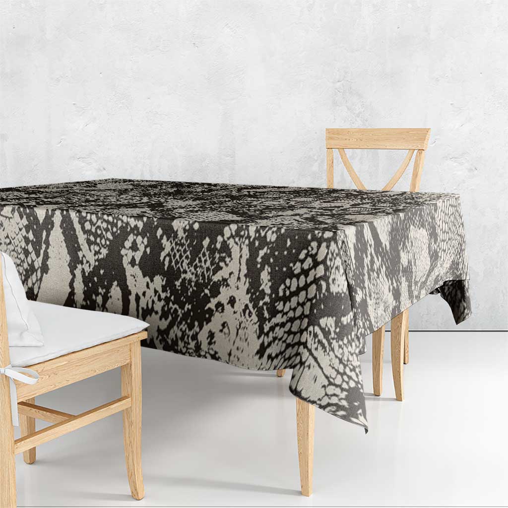 Black snake-and-crocodile print tablecloth draping over wooden dining table