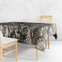 Black snake-and-crocodile print tablecloth draping over wooden dining table