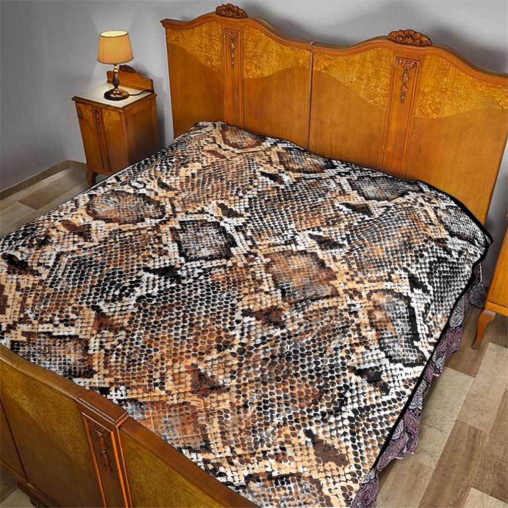 Snake-skin patterned quilt laid on bedspread, beige tan with black and white scales