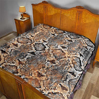 Snake-skin patterned quilt laid on bedspread, beige tan with black and white scales