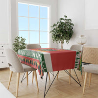 Red and green Christmas cat tablecloth draped over dining table edge with fringe border