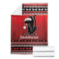 Red Iceland blanket with black cat centerpiece, white hat, and set with rolled white towels