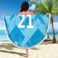 Blue round beach blanket with tassel fringe, lion crest and '21' with 'YOUR TEXT', held up.