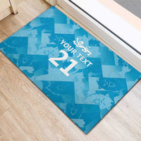 Blue rubber doormat corner view with 'YOUR TEXT 21' and lion crest on geometric pattern.