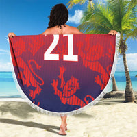 Round beach blanket with fringe, lion crest and large “21” on red-to-navy cricket pattern