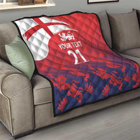 Red and navy custom quilt with Union Jack, lion crest, and 'YOUR TEXT 21' on sofa
