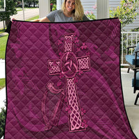 Maroon quilt with Celtic knot cross and quilted diamond pattern, displayed outdoors