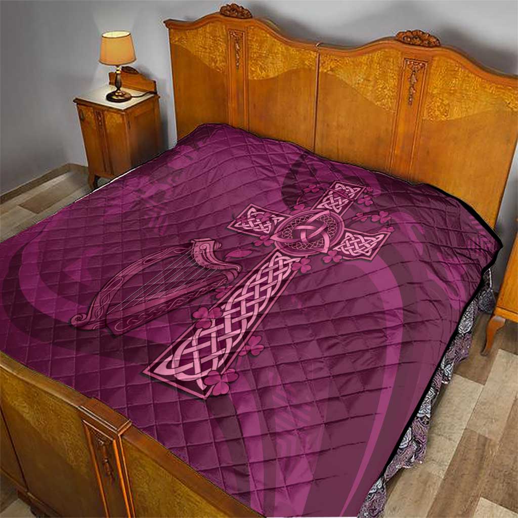 Maroon quilt with Celtic knot cross design laid across a bed