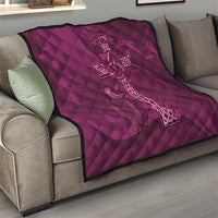 Maroon quilt with Celtic knot cross motif and quilted diamond pattern on a sofa