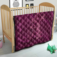 Maroon quilt with Celtic knot cross design on quilted diamond fabric in a crib