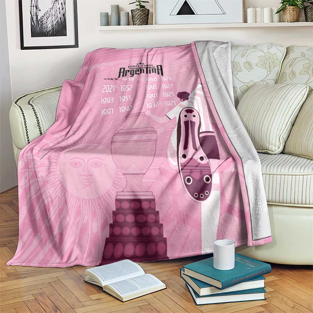 Pink Argentina football-themed blanket with graphic faces and trophy stacks, draped on sofa