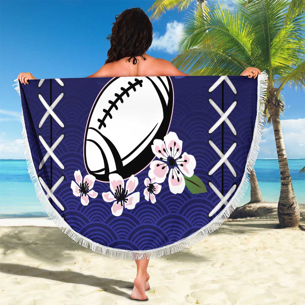 Round dark blue blanket with fringe, football and sakura pattern, held up outdoors