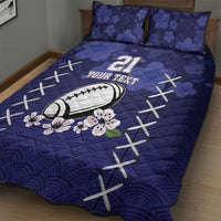 Blue quilt bed set with rugby ball and cherry blossom florals, white X stitching, and wavy pattern