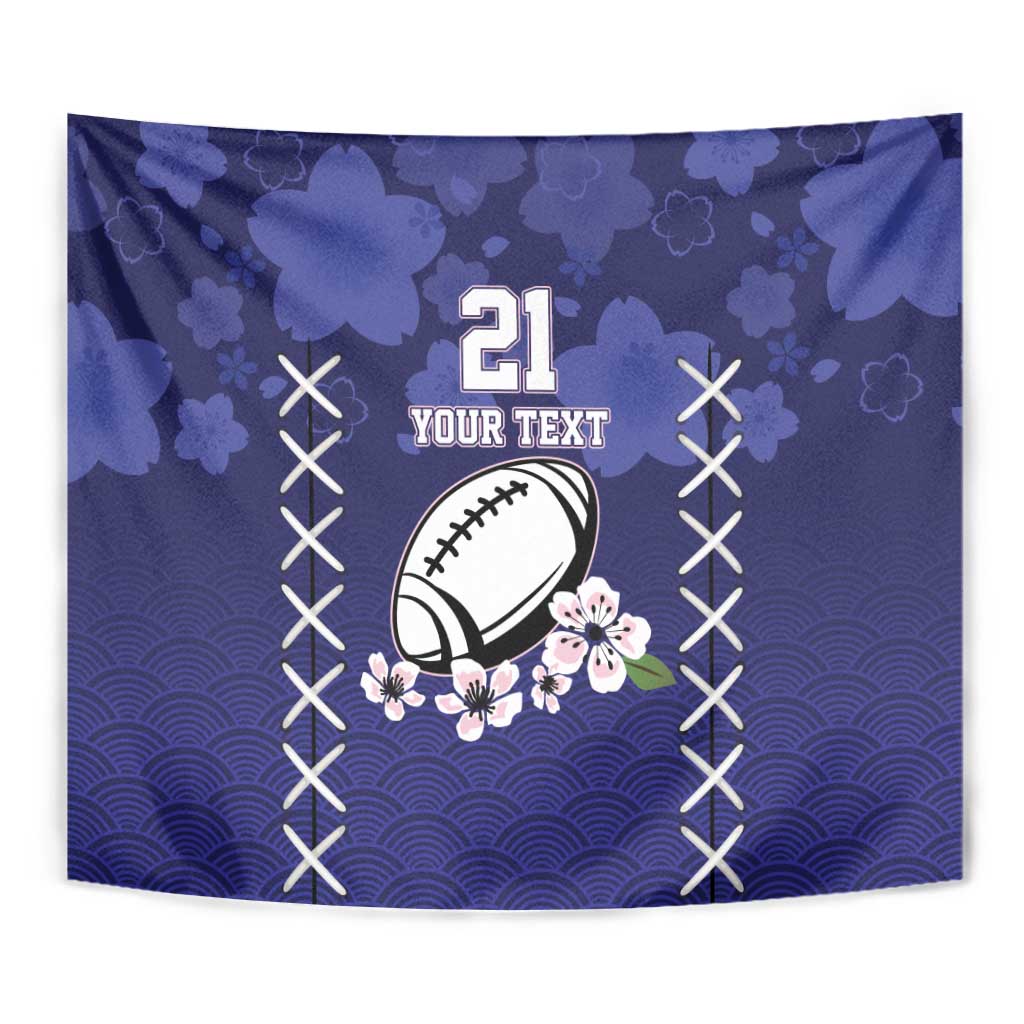 Blue tapestry wall hanging close-up showing rugby ball, sakura flowers, and rising-sun wave pattern.