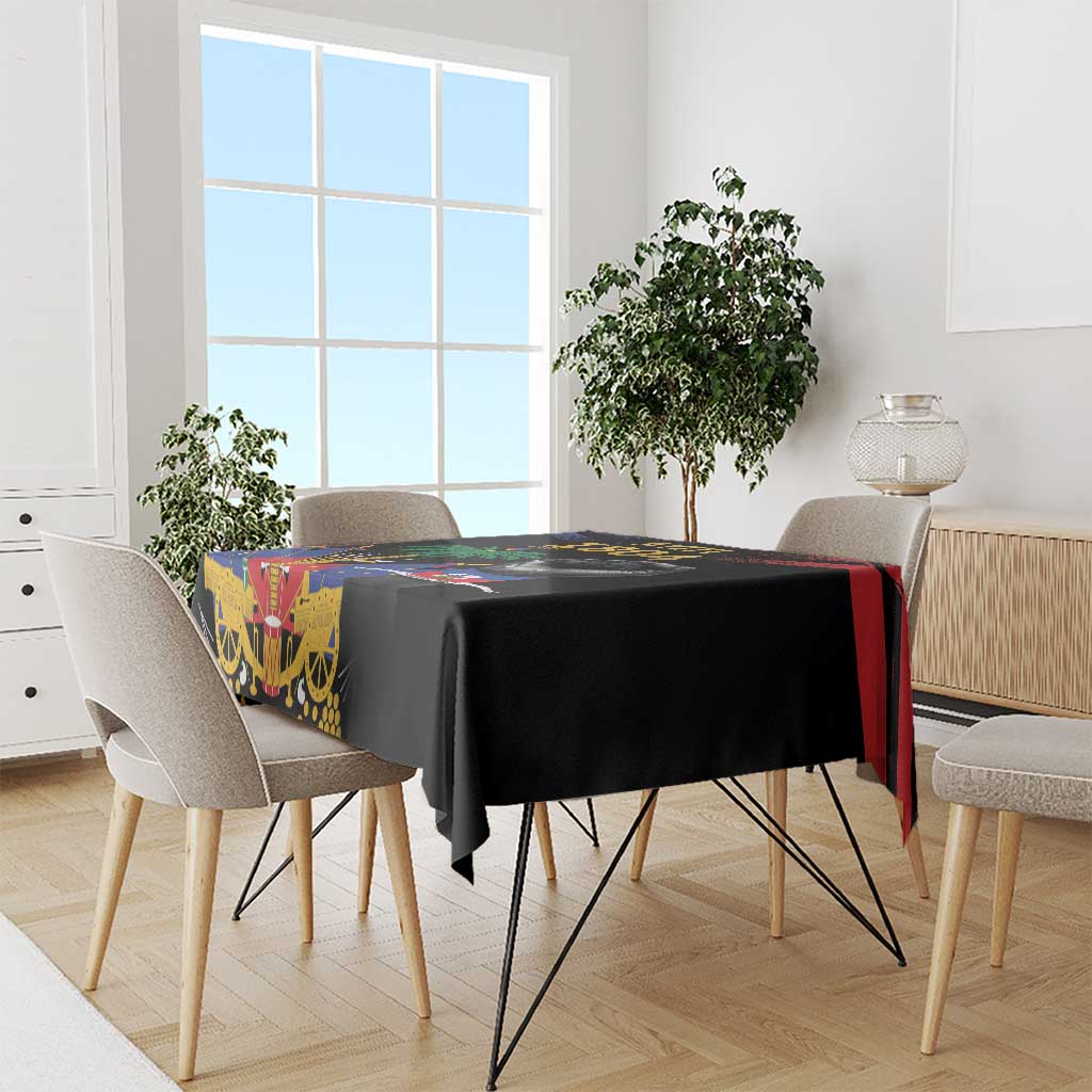 Black tablecloth with Haitian 1804 design draped over dining table with chair edges