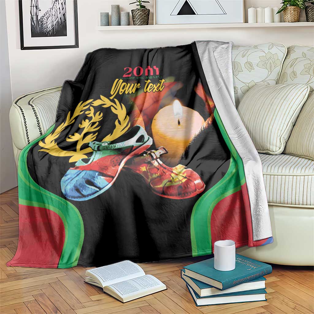 Black personalized blanket draped over couch with colorful Eritrea design, laurel, and candle
