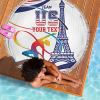 Round beach blanket with fringed edge, white base with blue tower and red gymnast graphic