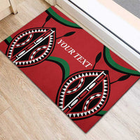 Red rubber doormat with 'YOUR TEXT' and tribal eye motifs in a doorway area