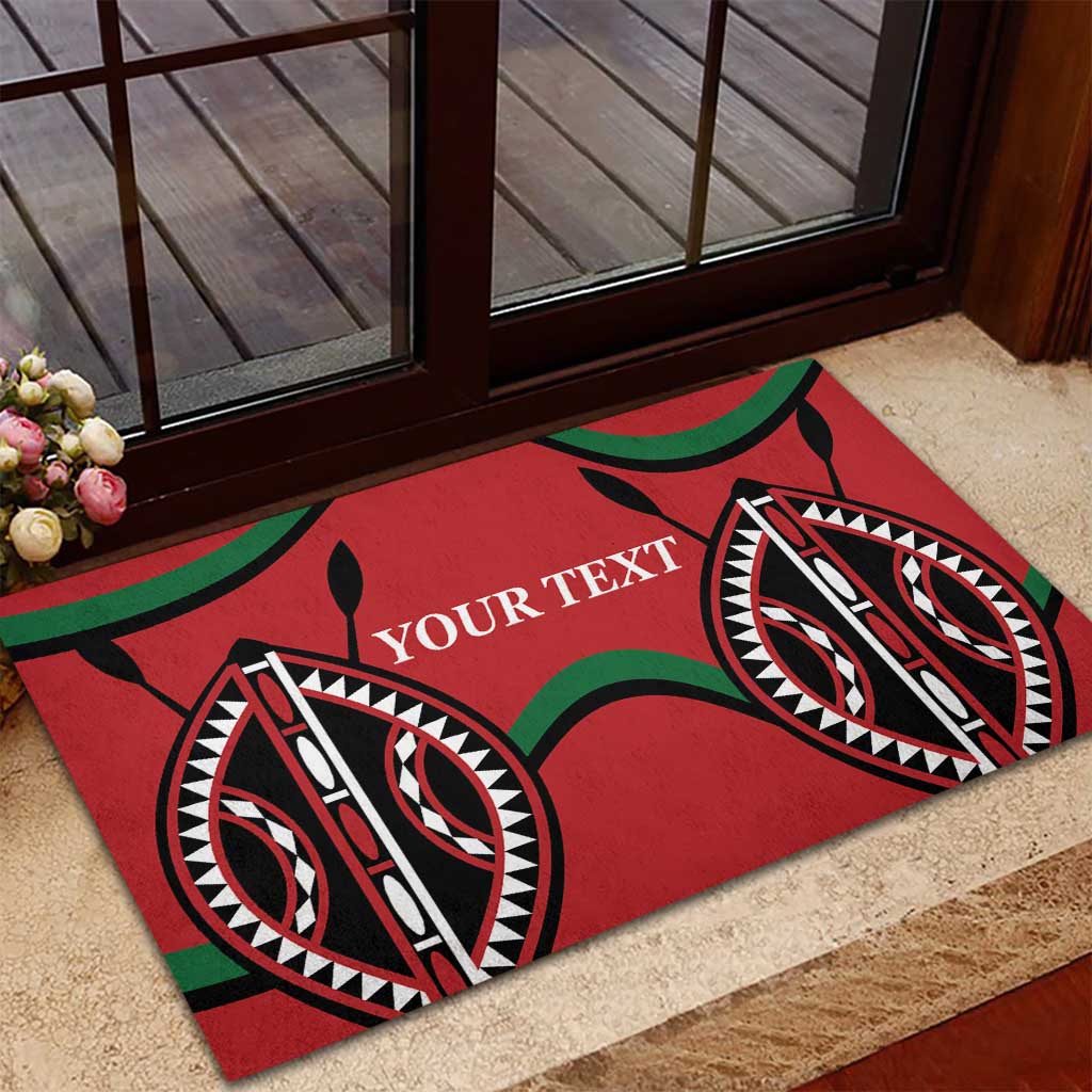Red rubber doormat with 'YOUR TEXT' and tribal eye motifs on a patio near a door
