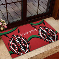 Red rubber doormat with 'YOUR TEXT' and tribal eye motifs on a patio near a door