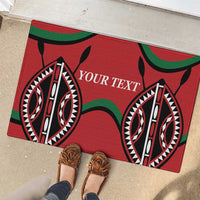 Red rubber doormat with 'YOUR TEXT' and tribal eye motifs beside shoes