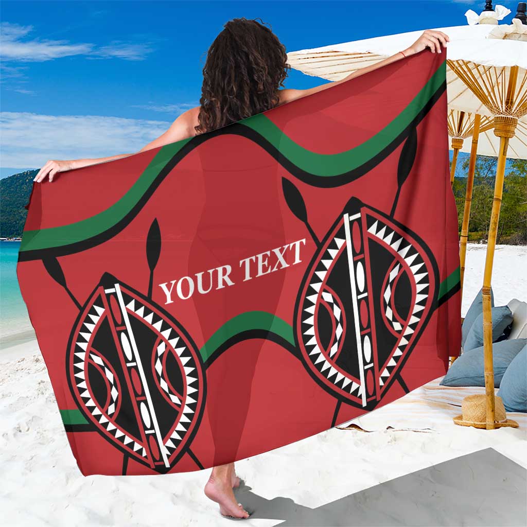 Red rugby sarong with green trim and large black-and-white eye motif, held out wide
