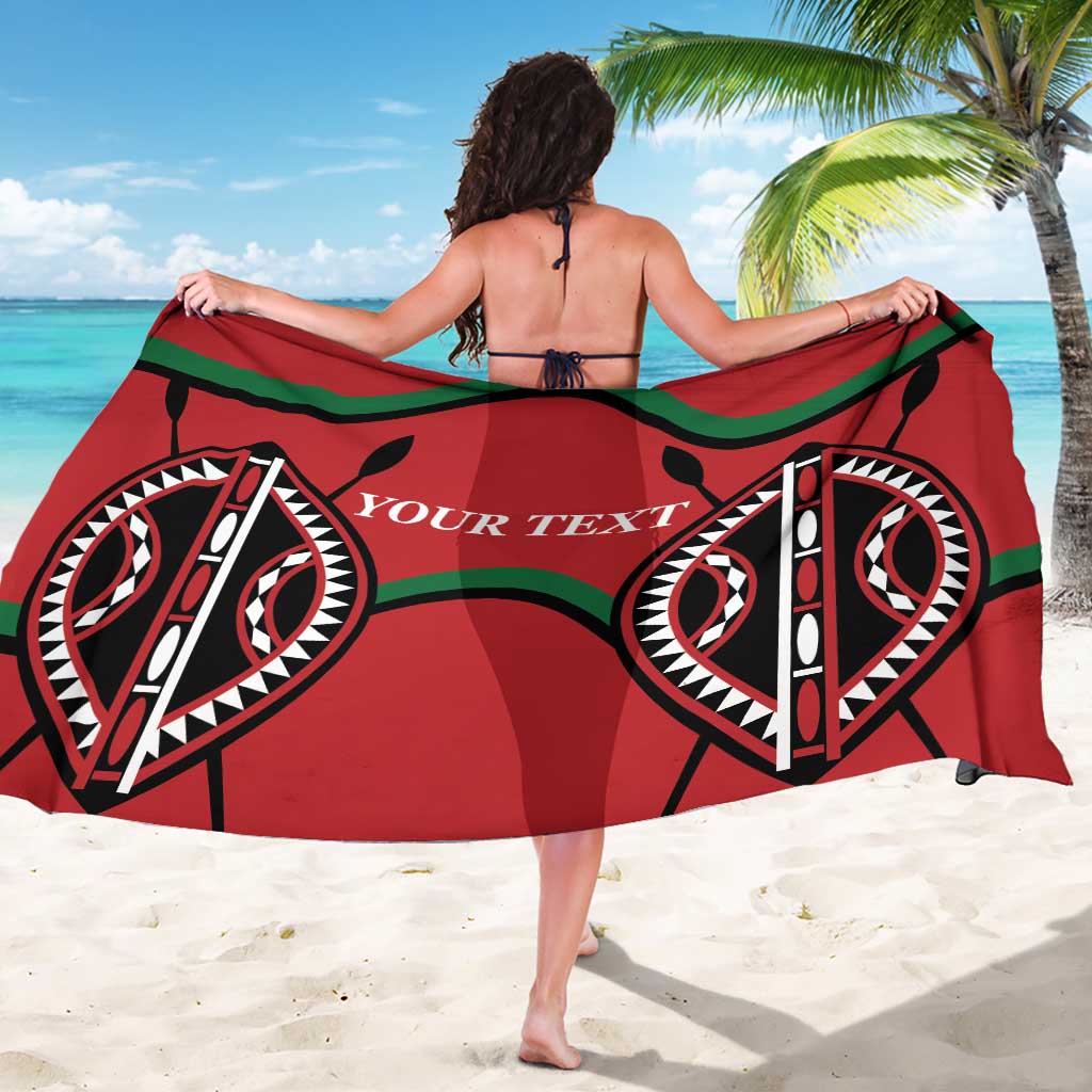Red and green tribal-pattern rugby sarong with bold circular motif, worn as a wrap