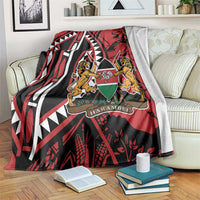 Red and black blanket with lions crest and geometric stripes, folded over couch back