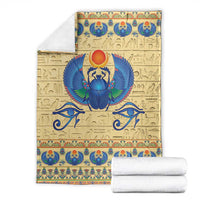 Beige scarab beetle blanket with blue winged scarab, ornate border, and folded white towels