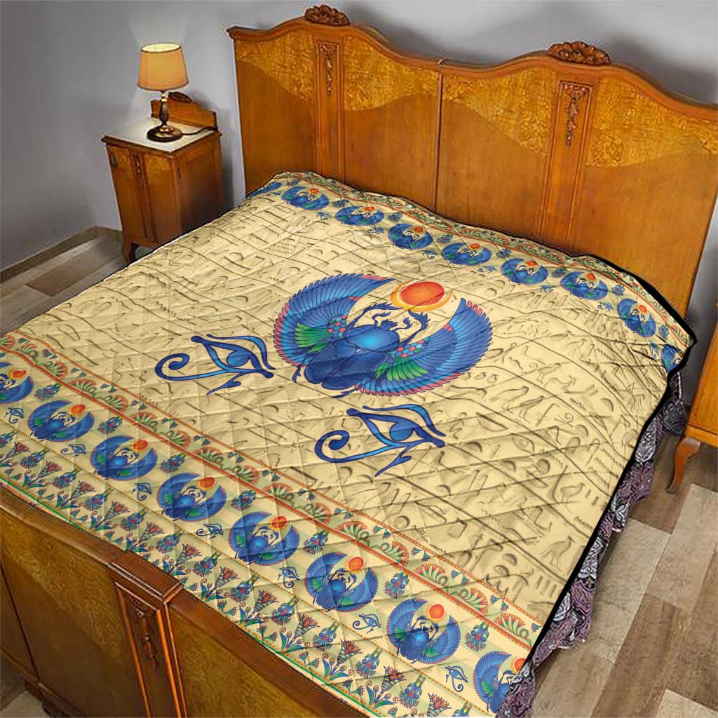 Beige bedspread quilt with blue winged scarab beetle center and patterned edge trim