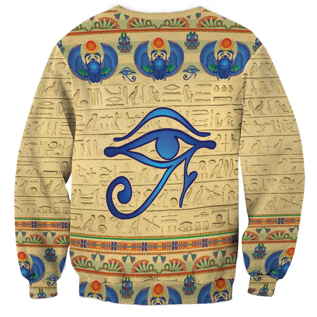 Beige sweatshirt with large blue eye motif and repeating Egyptian scarab beetle pattern
