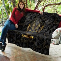 Black quilt draped with golden Anubis portrait, quilted diamond texture, 'ANUBIS' in gold.