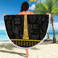 Round black beach blanket with gold ankh center and white tassel fringe, held outdoors