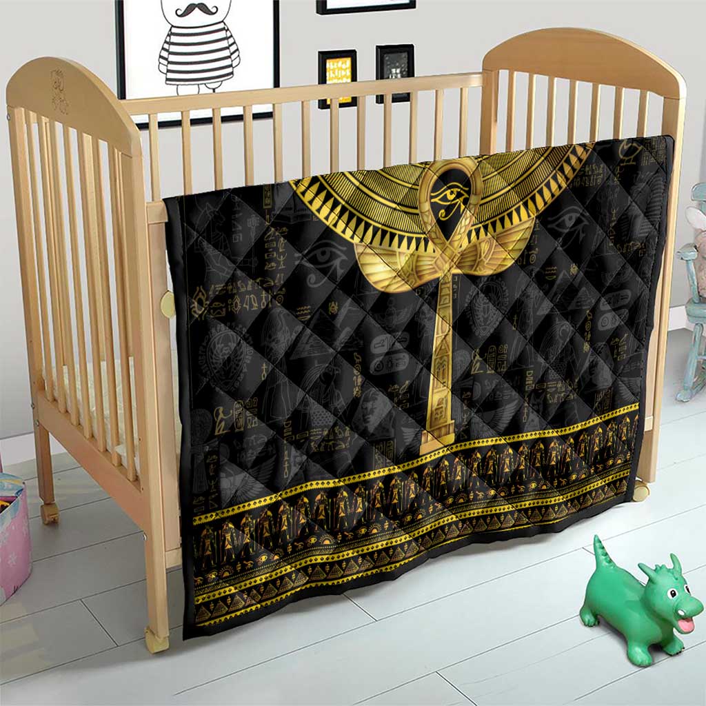 Black Egyptian hieroglyphs quilt with gold ankh motif, placed over a crib mattress