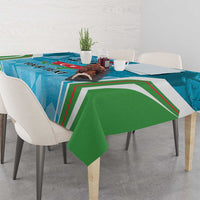 Blue tablecloth with green drape corners, printed stripes and emblem across table