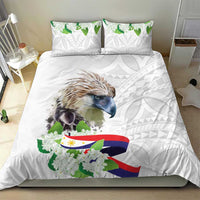 White bedding set with bird artwork, green leaf clusters, flag ribbon and light gray motif pillows