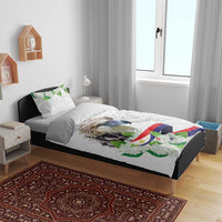 White bedding set on bed with bird, green floral details and flag ribbon print