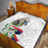 White diamond-stitched quilt on a bed, with eagle artwork, Philippine flag, and flowers.